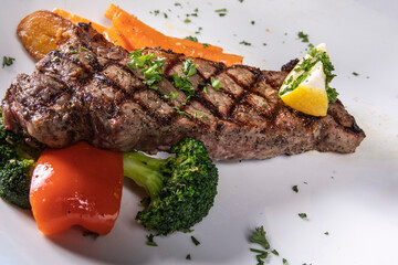 A grilled strip loin steak with vegetable garnish on a white table