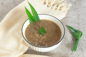 Mung Bean Porridge or Bubur Kacang Hijau, Indonesian dessert porridge of mung beans with coconut milk, pandan leaf and ginger. Served in white bowl.