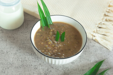 Mung Bean Porridge or Bubur Kacang Hijau, Indonesian dessert porridge of mung beans with coconut milk, pandan leaf and ginger. Served in white bowl.