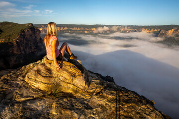 Young woman admiring misty canyon at sunrise