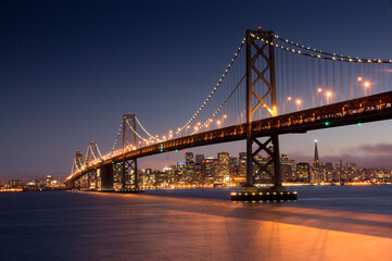 Night view of illuminated bridge against city skyline