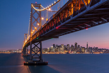 Illuminated city skyline and bridge at dusk