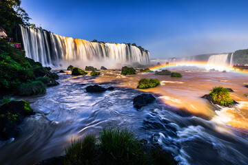 Majestic waterfall with rainbow at sunrise