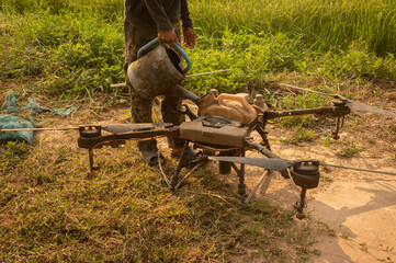 Farmer filling liquid fertilizer into a small tank of agriculture drone. This ability of drones...