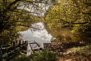 Panorama of a pond by the danube river in hungary with a wooden dock and a sunk old rowing boat in Duna Drava Nemzeti Park in Mohacs, Hungary. It's a Hungarian National Park by danube & drava rivers.
