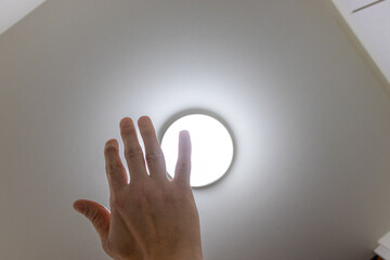 天井の照明の光を手で遮る