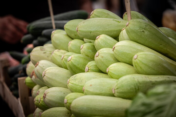 Selective blur on white zucchinis stacked for sale in a market of Belgrade, Serbia. Zucchini, or courgette, is a common vegetable and herbaceous plant.