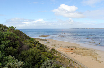 Beach, ocean and grassy green hill at Queenscliff in Victoria, Australia
