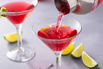Martini cocktail with cranberry juice garnished with lime twist
