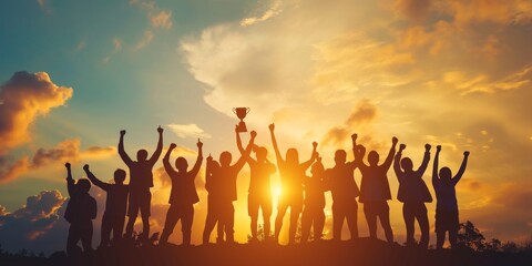 Success of teamwork. Winning team is holding trophy in hands. Silhouettes of many hands in sunset