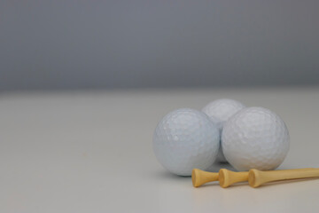three golf balls with golf tees on a white background, golf, golfing, summer sport, summer time