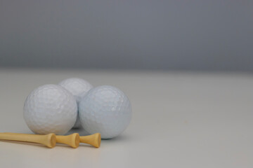 three golf balls with golf tees on a white background, golf, golfing, summer sport, summer time