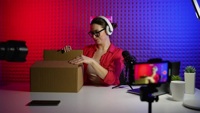 Female tech blogger unpacking box and recording video review of new Bluetooth speaker