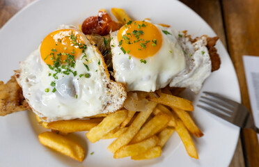FRIED FISH WITH FRIED POTATOES, FRIED ONION AND FRIED EGG ON A PLATE WITH A FORK