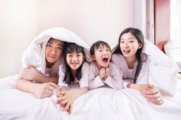 Fototapeta premium A family of four in bed in the bedroom