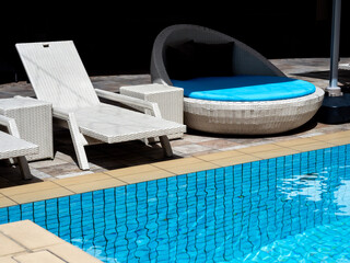 Empty white modern rattan sunbeds chair, and waterproof round lie bed with blue seat cushion for...