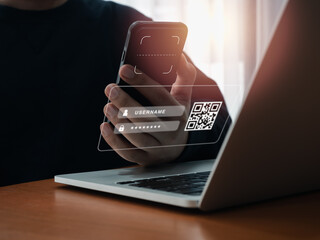 QR Code, multi factor authentication security concept. Digital scanner, graphic symbol on smartphone camera lens holding by businessman hand, scanning for login on virtual screen from laptop computer.