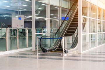 Modern escalators with staircase at airport. The passage is closed with restrictive tape