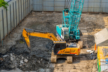 Excavators during earthworks at construction site. Backhoe the digging pit for construct building foundation. Construction machinery for excavating, loading, lifting and hauling
