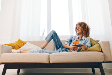 Happy woman holding mobile phone, enjoying online games and reading messages on sofa at home
