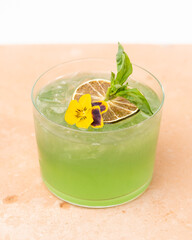 Green Craft Cocktail With Flower and Lime Garnish