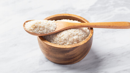Psyllium husk in spoon on wooden bowl on white marble table
