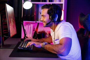 Smart gaming streamer enjoy playing battle team with streaming online shooting gun game with multi or single player at warship on pc screen, wearing headset at digital neon light cyber room. Surmise.