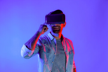 Man wearing virtual reality headset while enter in metaverse. Caucasian man standing at colorful neon light and using futuristic digital technology virtual goggles or VR for playing games. Deviation.