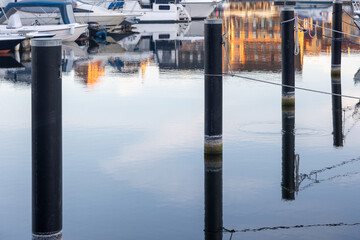 A row of mooring piles or dolphins mirroring in smooth and glassy water