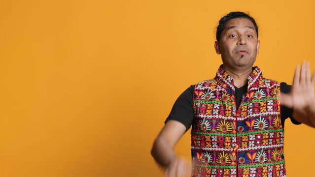 Stern indian man doing stop hand gesture sign, complaining. Authoritative person doing firm halt sign gesturing, wishing to end concept, isolated over studio background, camera A