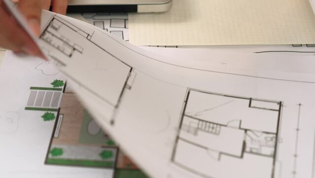 Professional engineer team discussion about house design on meeting table with architectural equipment and building blueprint scatter around at modern office. Focus on hand. Closeup. Delineation.