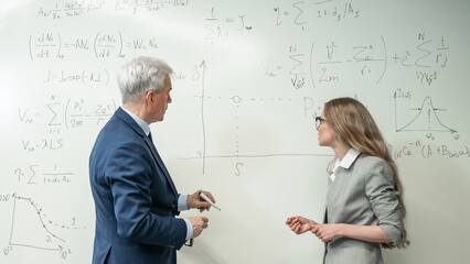 Female student answers a question from an elderly professor at a white board. 