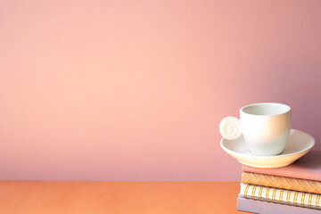 Stack of notebook and coffee cup on orange table. pink wall background with copy space