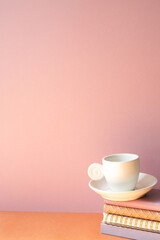 Stack of notebook and coffee cup on orange table. pink wall background with copy space