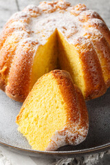 Close-up of Meskouta orange pound cake with powdered sugar on a plate on the table. Vertical