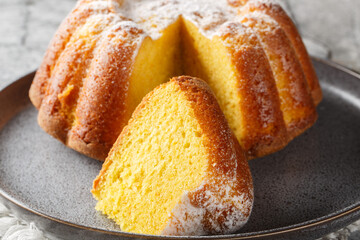 Delicious orange pound cake with zest and orange juice, sprinkled with powdered sugar on a plate on the table. Horizontal