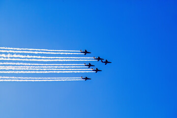Aircrafts in formation flight with white condensation trails on a blue sky