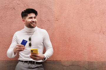 Man using credit card to pay online in a e-commerce with his cellphone. Copy space.