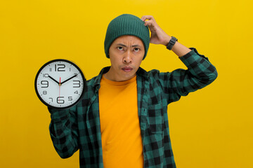 A young Asian man, clad in a beanie hat and casual shirt, holds a clock and looks shocked at the...