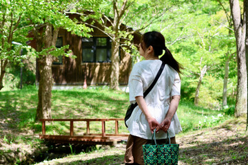新緑の森や公園を散歩する女性と風景　緑の背景　ログハウス