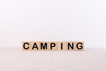 Word CAMPING made with wood building blocks on a light background