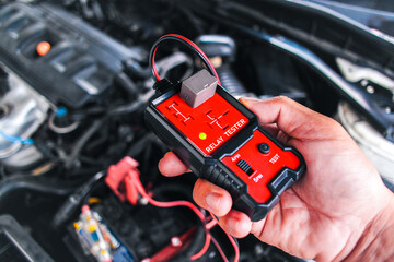 Car relay testing with a relay tester , relay tester in a mechanic hand for system test , Car maintenance and repair servicing concept