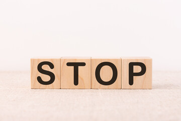 STOP word concept written on wooden cubes blocks lying on a light table and light background