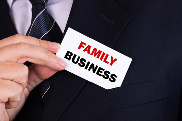 Obraz premium Businessman putting a card with text family business in the pocket
