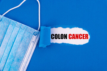 The text Colon Cancer appearing behind torn blue paper.
