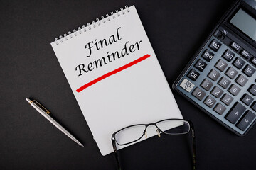 Final Reminder notepad writing concept on dark background with pen and calculator.