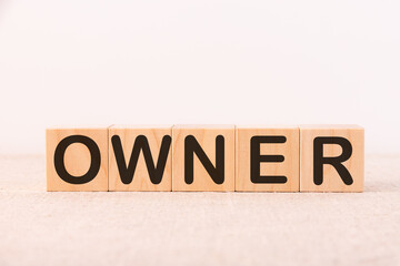 OWNER word concept written on wooden cubes blocks lying on a light table and light background