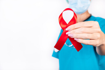 Red ribbon in a doctor's hand as a symbol of help awareness on a white background.