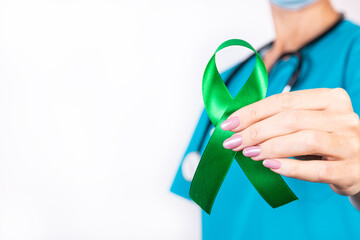 Kidney Cancer Awareness Month concept. Green ribbon awareness symbolic concept on doctor hand.