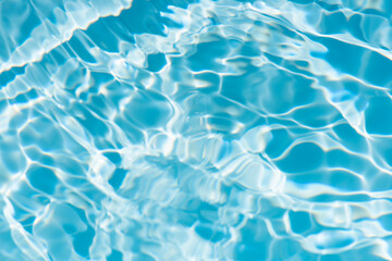 Blue water with ripples on the surface. Defocus blurred transparent blue colored clear calm water surface texture with splashes and bubbles. Water waves with shining pattern texture background.